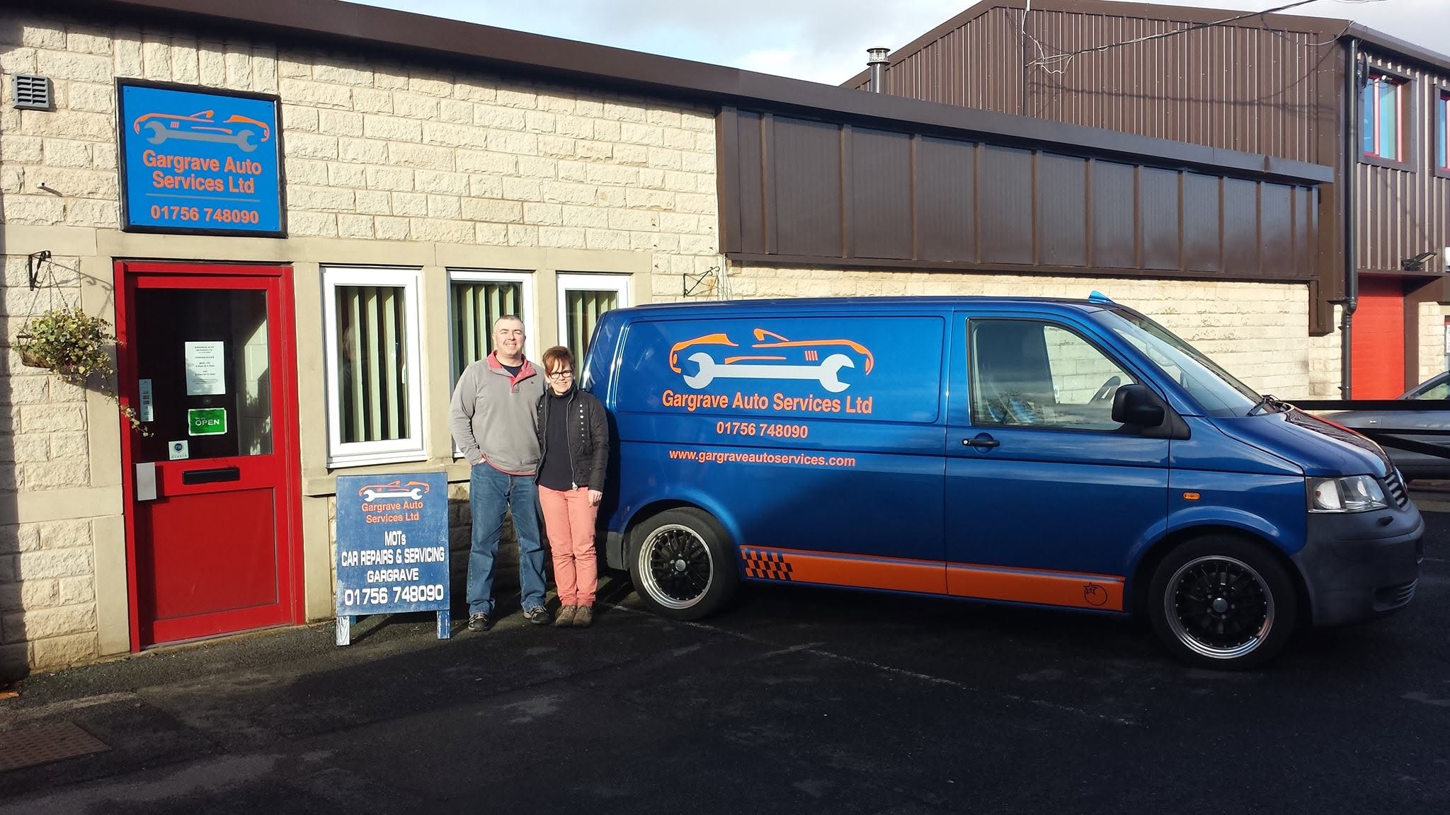 Simon and Lisa outside Gargrave Auto Services with the blue company van and A-board