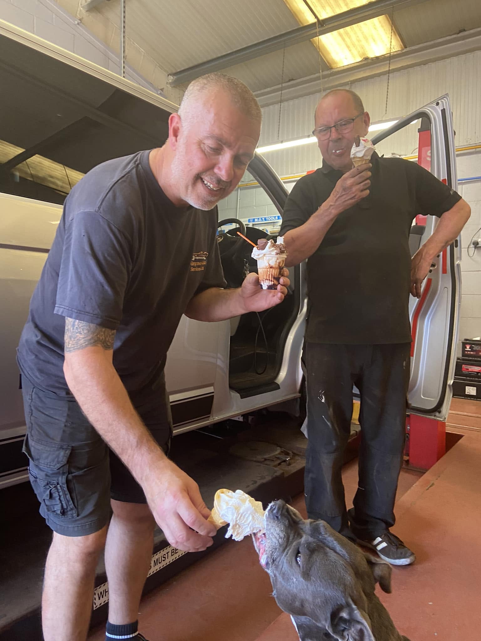 Two men in the workshop sharing ice creams with a dog