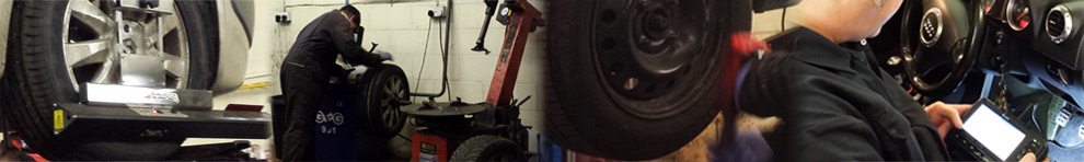 Inside the workshop: a car on alignment heads, a tyre changer and a diagnostic tablet in use